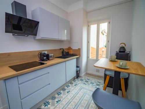 une cuisine avec des placards blancs, une table et un comptoir dans l'établissement #202-Heart of Vieil Antibes - Place Nationale-High-End Newly Renovated & Furnished Appartment, à Antibes