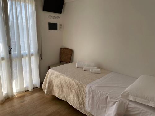 a white bedroom with a bed and a chair at Hotel Barbiani in Riccione