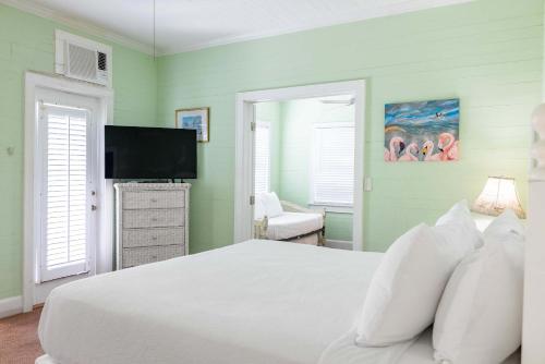 a bedroom with a white bed and a flat screen tv at King Suite Balcony - at James House in Key West