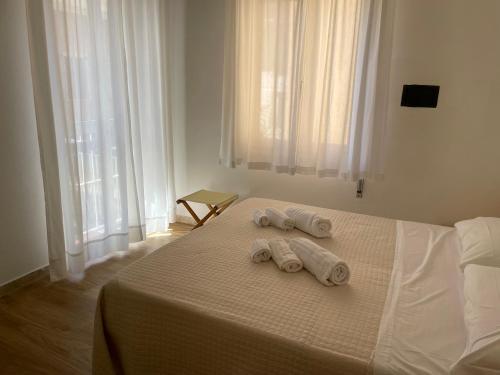 two towels on a bed in a room with windows at Hotel Barbiani in Riccione