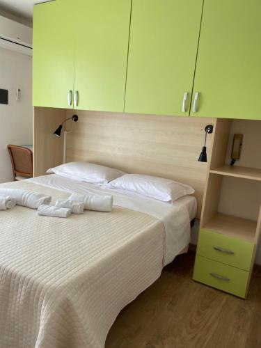 a bedroom with a large white bed with green cabinets at Hotel Barbiani in Riccione