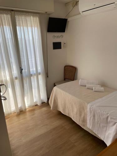 a bedroom with a bed and a window with white curtains at Hotel Barbiani in Riccione