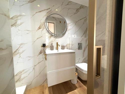 une salle de bain blanche avec un lavabo et un miroir dans l'établissement Palais Miramar Croisette 2 BRD Gold Suite, à Cannes