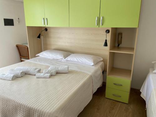 a bedroom with a large white bed with green cabinets at Hotel Barbiani in Riccione
