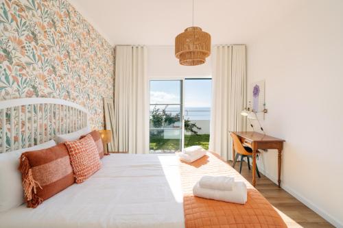 a bedroom with a bed with a desk and a window at Sunrise House by Wanderlust Madeira - 2 Bedroom Sea View in Gaula