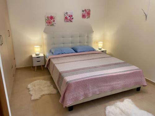 a bedroom with a large bed with two lamps and rugs at Eukalyptos 3BD apartment with yard in Chersonisos in Hersonissos