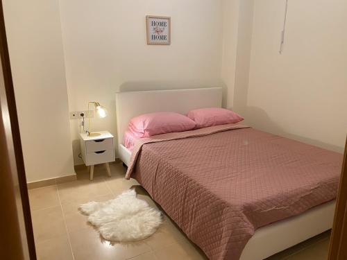 a bedroom with a bed with pink sheets and a white rug at Eukalyptos 3BD apartment with yard in Chersonisos in Hersonissos