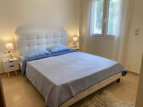 a bedroom with a large bed with blue pillows and a window at Eukalyptos 3BD apartment with yard in Chersonisos in Hersonissos