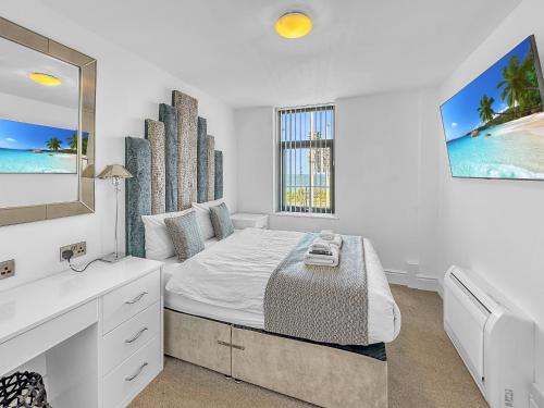 a white bedroom with a bed and a window at Granada Apartments Berkeley in Blackpool