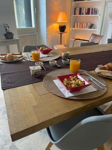 a wooden table with a plate of food and orange juice at Maison d'hôtes la Doma Venterol chambres & SPA in Venterol