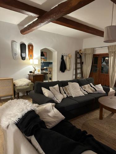 a living room with a black couch and white pillows at Za Lasem Nad Wodą in Narty