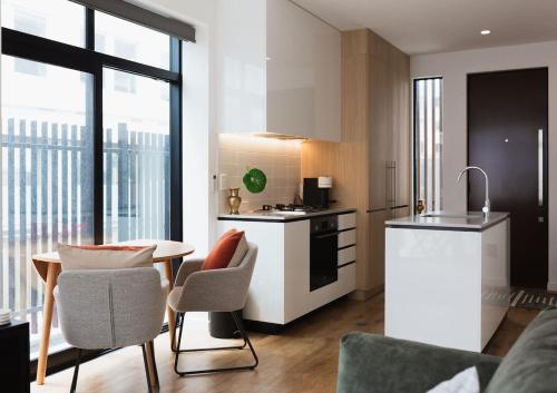 a kitchen with a table and some chairs in a room at Chic 2BR Apartment - Secure Gated Complex in CBD in Wellington