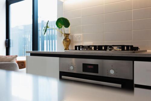 a kitchen with a stove top oven in a room at Chic 2BR Apartment - Secure Gated Complex in CBD in Wellington