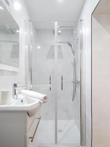 une salle de bain blanche avec une douche et un lavabo dans l'établissement Suite Art de Vivre - Studio calme et central, à Argenteuil
