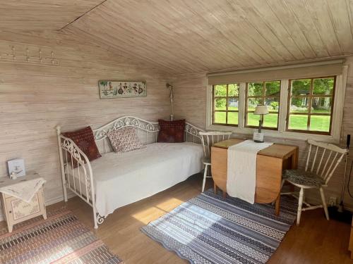a bedroom with a bed and a desk and windows at Naturnära Fritidsboende, Tomtebo - YinTorp in Arkelstorp