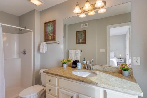 a bathroom with a sink and a toilet and a mirror at Sleeps 28 Beachfront w Pool Hot Tub Game Room Atlantic Watch by AvantStay in Kill Devil Hills