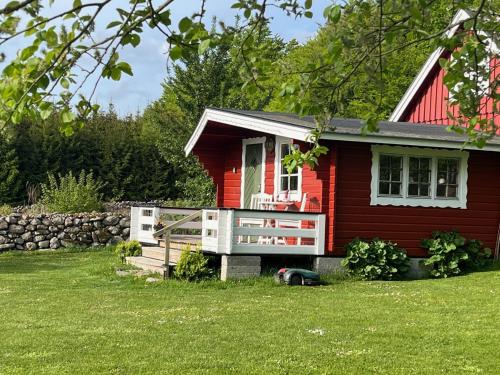 a red house with a large porch in the yard at Naturnära Fritidsboende, Tomtebo - YinTorp in Arkelstorp