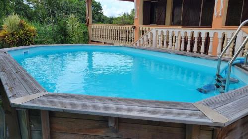 a swimming pool with a wooden bench next to a house at résidence Pom'kanel in Sainte-Rose