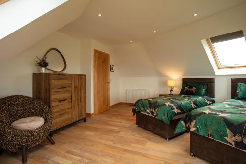 a bedroom with two beds and a chair and a window at Gualan Sands in Clachan