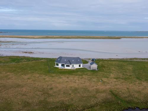 a house in a field next to the water at Gualan Sands in Clachan