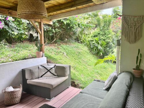 a patio with a couch and a chair on a deck at Maison Bois Jolan Sainte Anne in Sainte-Anne