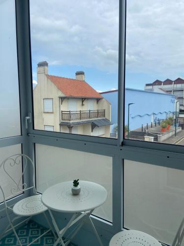 a table and two chairs in a room with windows at L'Echappée Quennoise, Appartement à 200m de la mer in Quend-Plage