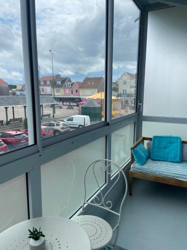 a balcony with a table and a couch and windows at L'Echappée Quennoise, Appartement à 200m de la mer in Quend-Plage