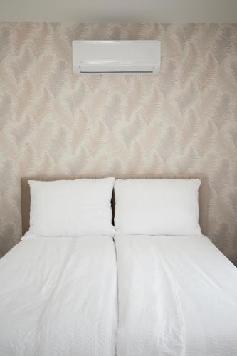a bed with two pillows and a light above it at Bovi Lux Apartman in Nyíregyháza