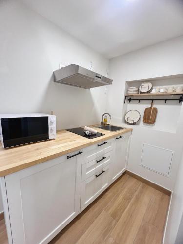 une cuisine avec des armoires blanches et un micro-ondes dans l'établissement Japandi en centre-ville, à Narbonne