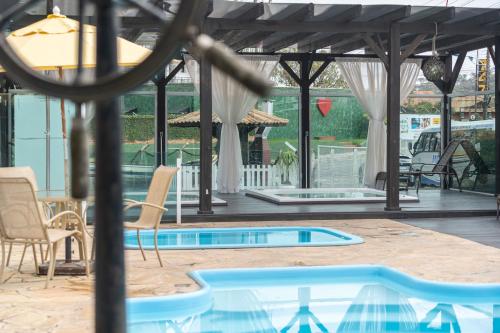 a swimming pool with chairs and a pavilion at Pousada Quinta da Baleeira in Penha
