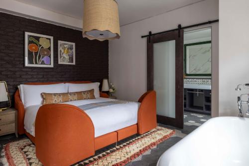 a bedroom with an orange bed and a bathroom at Virgin Hotels London - Shoreditch in London