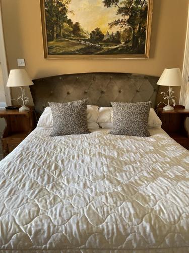 a large white bed with two pillows and a painting at The Eagle Tavern in Faringdon