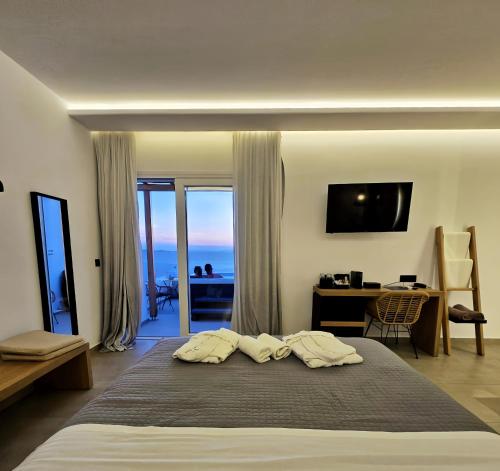 a bedroom with a bed and a desk with a view at Avra Mykonos in Tourlos