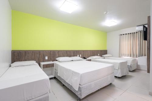 a room with three beds and a green wall at Pousada Quinta da Baleeira in Penha