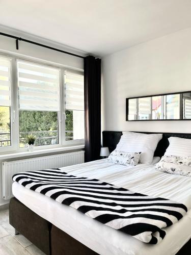 a large bed in a white room with windows at U Borsuków in Pobierowo