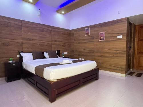 a bedroom with a large bed with a wooden wall at Chilanka Lake View Resort in Alleppey