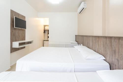 a bedroom with two beds and a tv on the wall at Pousada Quinta da Baleeira in Penha