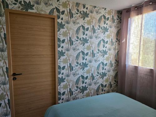 a bedroom with a door and a floral wallpaper at Appartement paisible à 300m de la plage in Le Grau-du-Roi