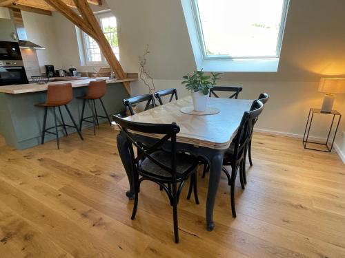 a dining room table with chairs and a kitchen at Le Hêtre Rouge Charme & Spa Alsace in Barr
