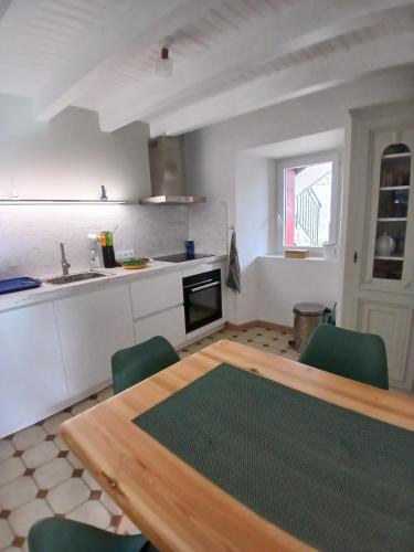 une cuisine avec une table en bois et des chaises vertes dans l'établissement Maison de campagne, à Séneujols
