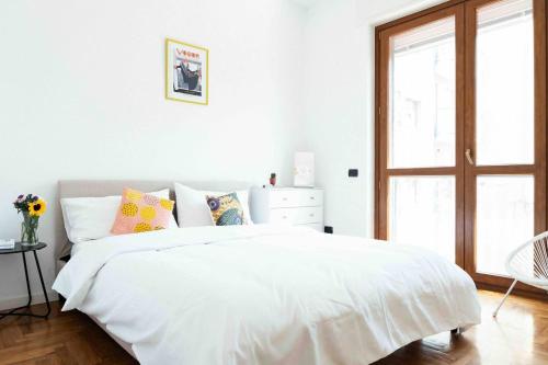 a white bedroom with a large white bed with pillows at Oasi di Famagosta Milano Navigli in Milan