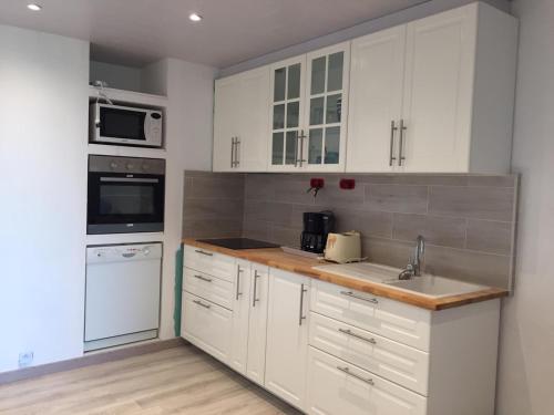 une cuisine avec des armoires blanches et des appareils électroménagers blancs dans l'établissement Carpe diem, à Port-Leucate