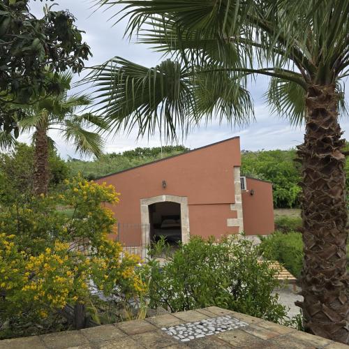 a building with a palm tree in front of it at Al Palmento Relais in Siracusa