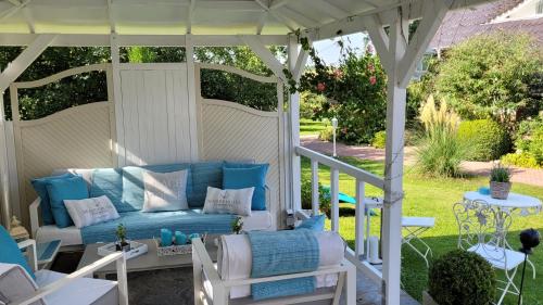 a white pergola with a blue couch on a patio at Apartmenthaus Storchennest in Katzow