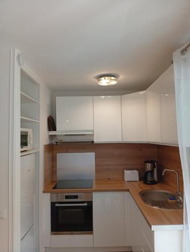 une petite cuisine avec des armoires blanches et un évier dans l'établissement Appart à deux pas de la plage Boulouris St Raphael, à Saint-Raphaël