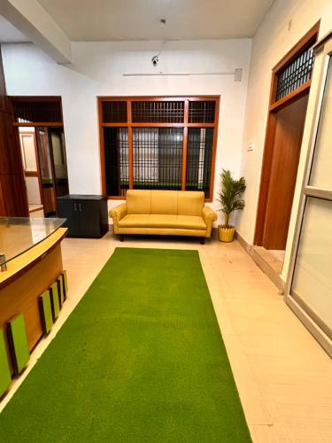 a living room with a yellow couch and a green rug at Shri Shyam Kunj in Ayodhya