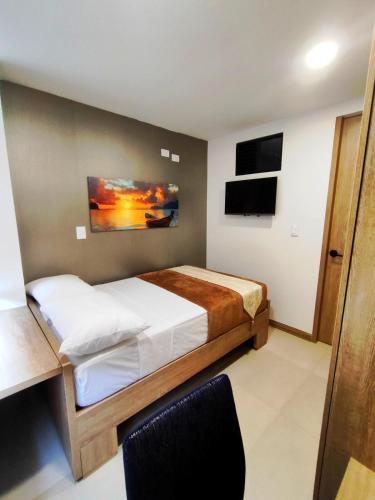 a bedroom with a bed and a desk and a tv at Apartment - 5 minutes from the airport in Pereira