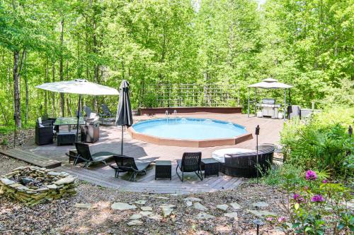 a patio with a pool and chairs and an umbrella at Hot Tub and Trail Access Treehouse in Landrum! in Landrum