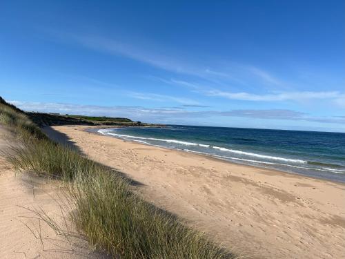 a sandy beach with the ocean in the background at Sea Breeze St Combs in Fraserburgh