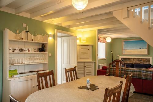 a dining room with a table and a living room at Taigh Phinc in Paible